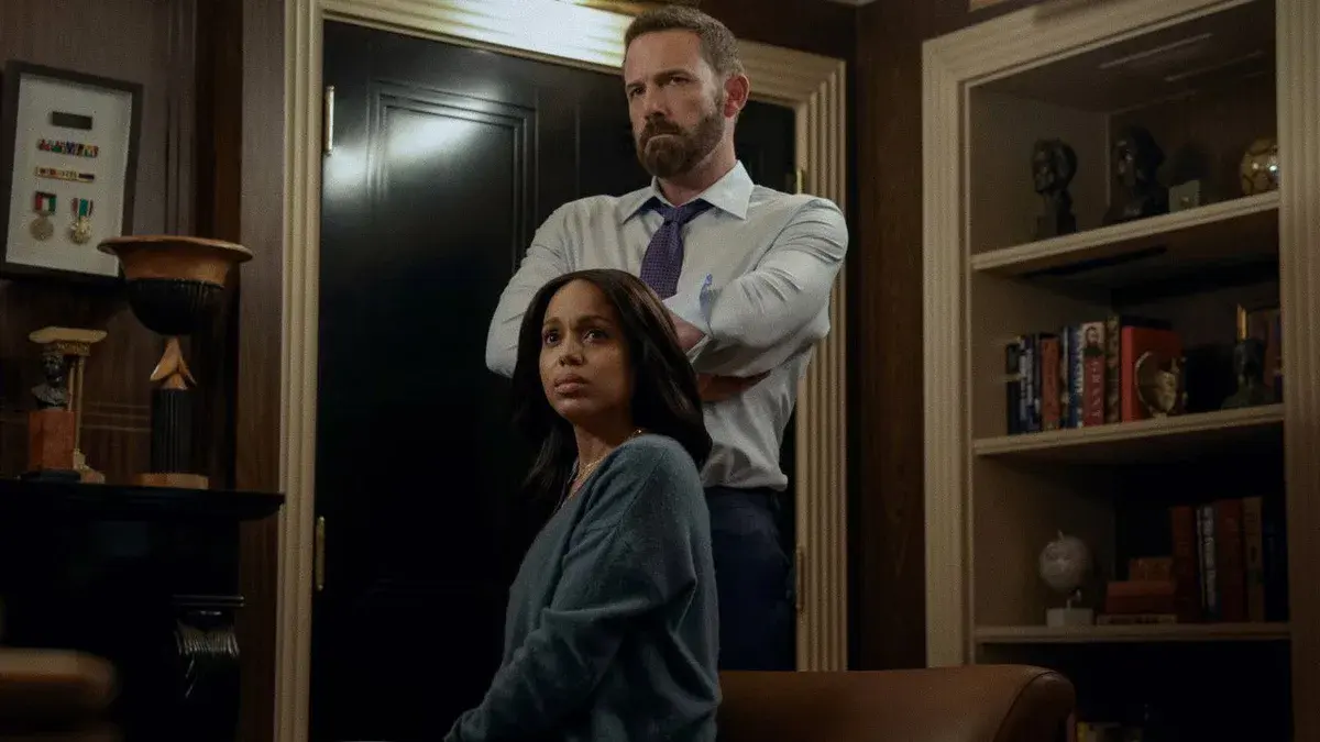 Ben Affleck, bras croisés en chemise et cravate, debout derrière Kerry Washington assise et inquiète dans un bureau, dans le film Animals