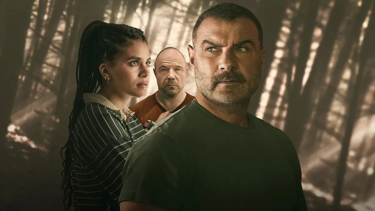 Liev Schreiber au premier plan, Zazie Beetz et Stephen Graham derrière lui, devant une forêt dans la brume, sur un visuel de la série Nocturne d'Apple TV