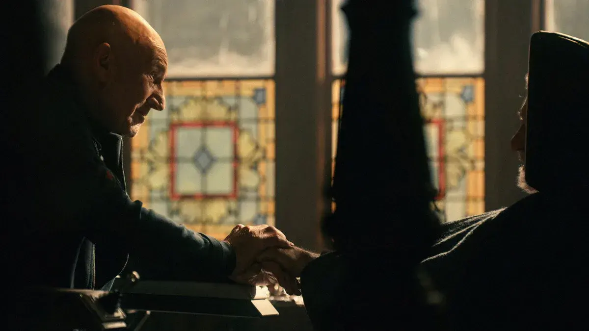 Charles Xavier, joué par Patrick Stewart, serre la main d'une silhouette restée dans l'ombre devant un vitrail dans Avengers : Doomsday