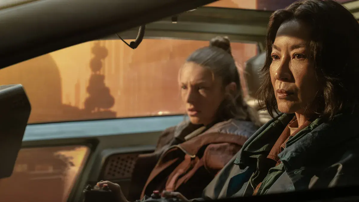Hunter Schafer (Cora) et Michelle Yeoh (Olwen) dans un véhicule face à un Los Angeles orangé, dans Blade Runner 2099