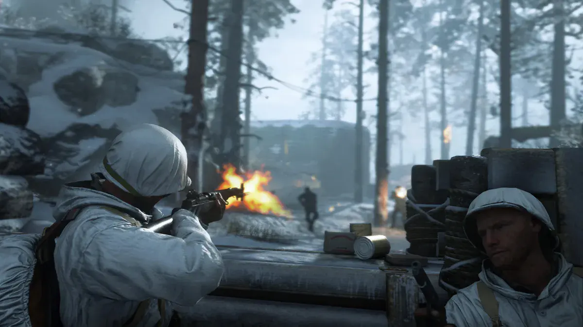 Deux soldats américains en tenue de camouflage blanche tirent depuis un abri de rondins dans une forêt enneigée, dans Call of Duty: WWII