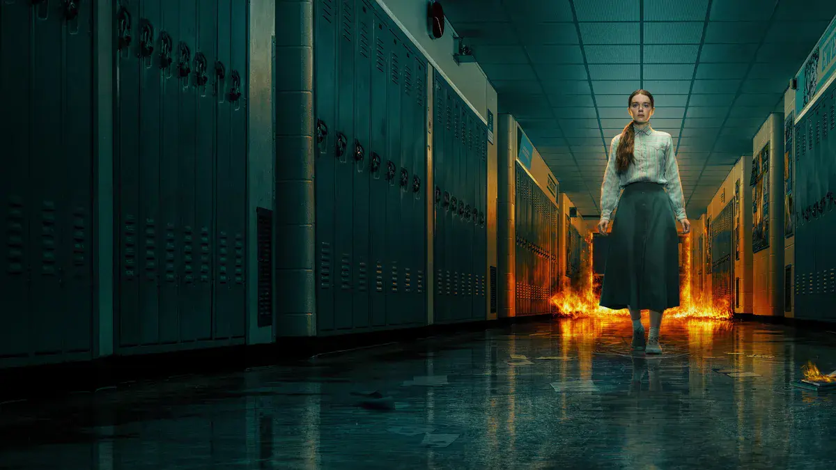 Summer H. Howell en Carrie White dans un couloir de lycée, des flammes à ses pieds, dans la série Carrie de Prime Video