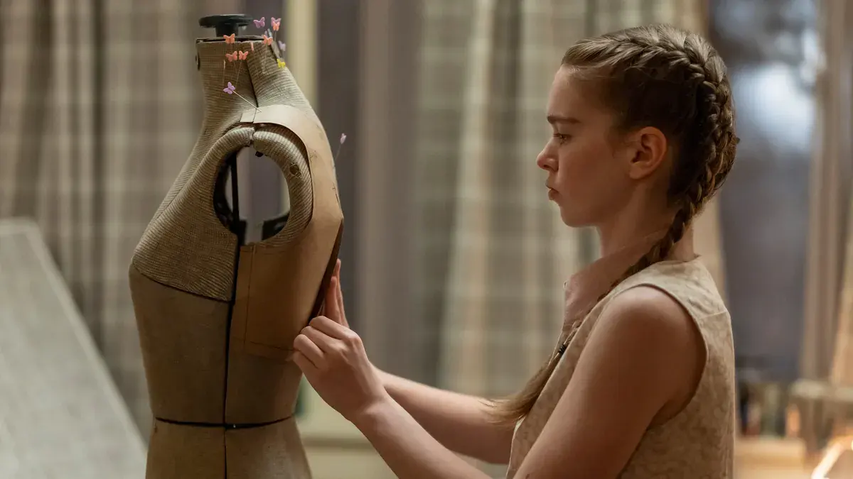 Summer H. Howell en Carrie White ajuste une robe sur un mannequin de couture, dans la série Carrie de Prime Video