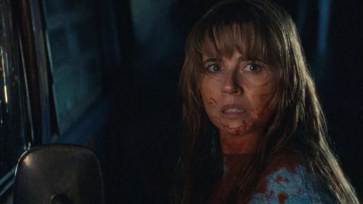 Linda Cardellini en Pamela Voorhees, le visage taché de sang, de nuit au volant d'une voiture dans la série Crystal Lake