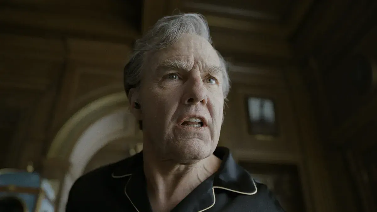 Tom Cruise, vieilli, en pyjama de soie noire, le visage crispé dans un couloir lambrissé de Digger