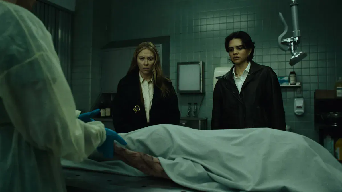 Scarlett Johansson et Sasha Calle, en manteaux sombres, regardent un corps recouvert d'un drap à la morgue dans The Exorcist: Martyrs