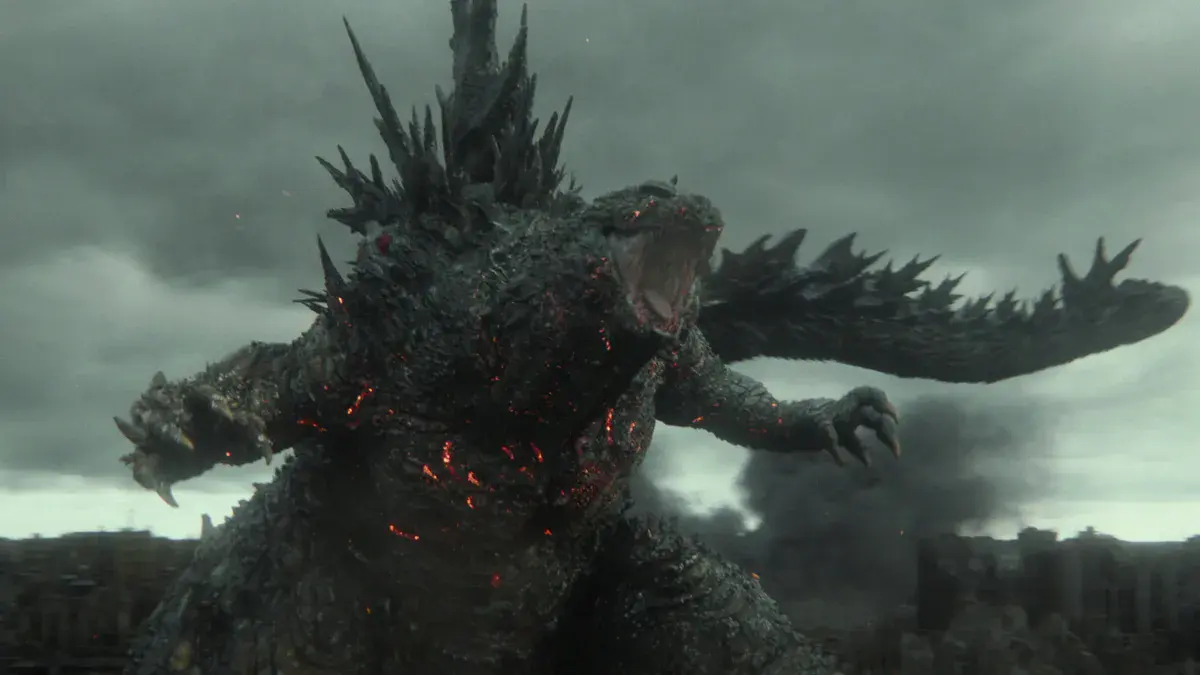 Godzilla, le dos hérissé de plaques et le corps strié de lueurs rouges, rugit au-dessus d'une ville en fumée dans Godzilla Minus Zero