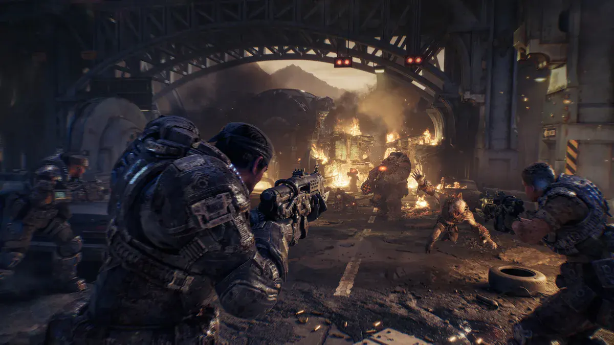 Un soldat de la CGO au bandana et son escouade tirent sur des Locustes dans une rue en flammes, dans Gears of War: E-Day