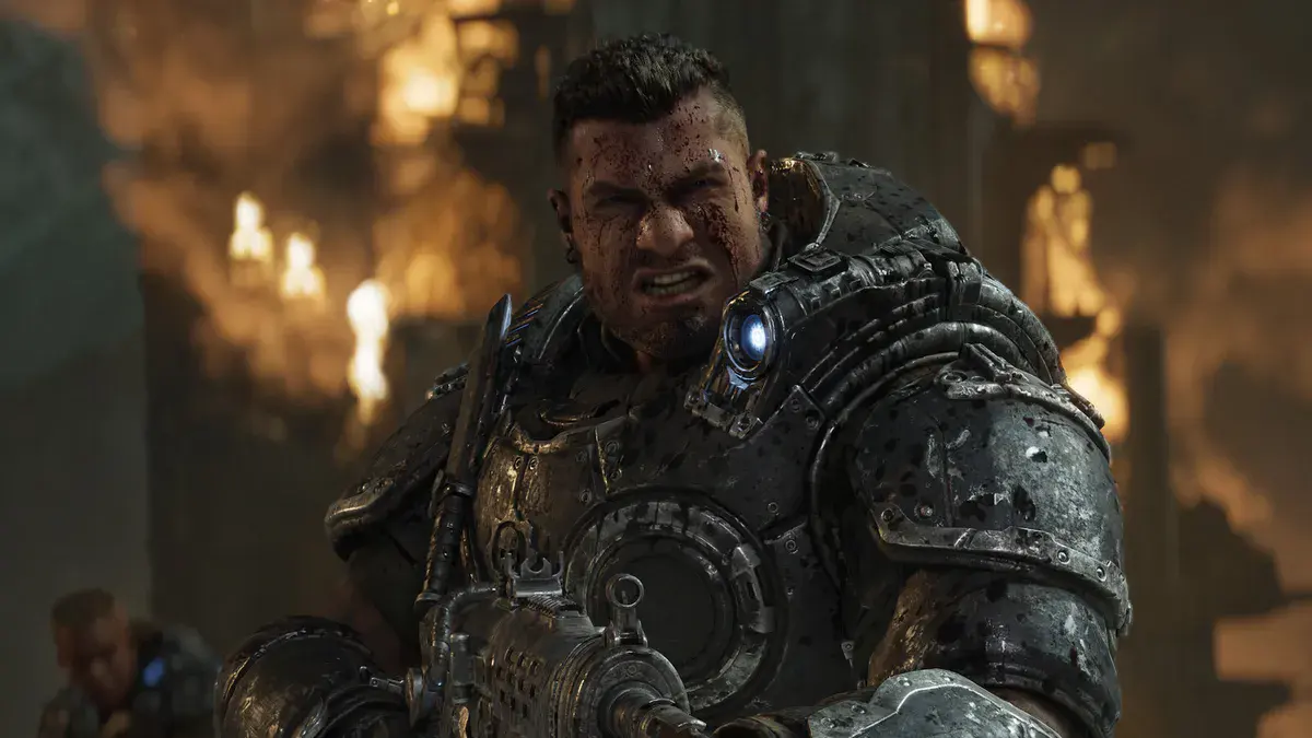Un Gear au visage ensanglanté serre les dents, Lancer en main, devant un décor en flammes dans Gears of War: E-Day