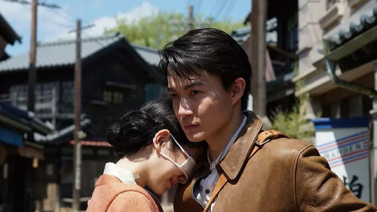 Godzilla Minus Zero : Koichi Shikishima, en blouson de cuir, serre contre lui une jeune femme masquée dans une rue du Japon de l'après-guerre