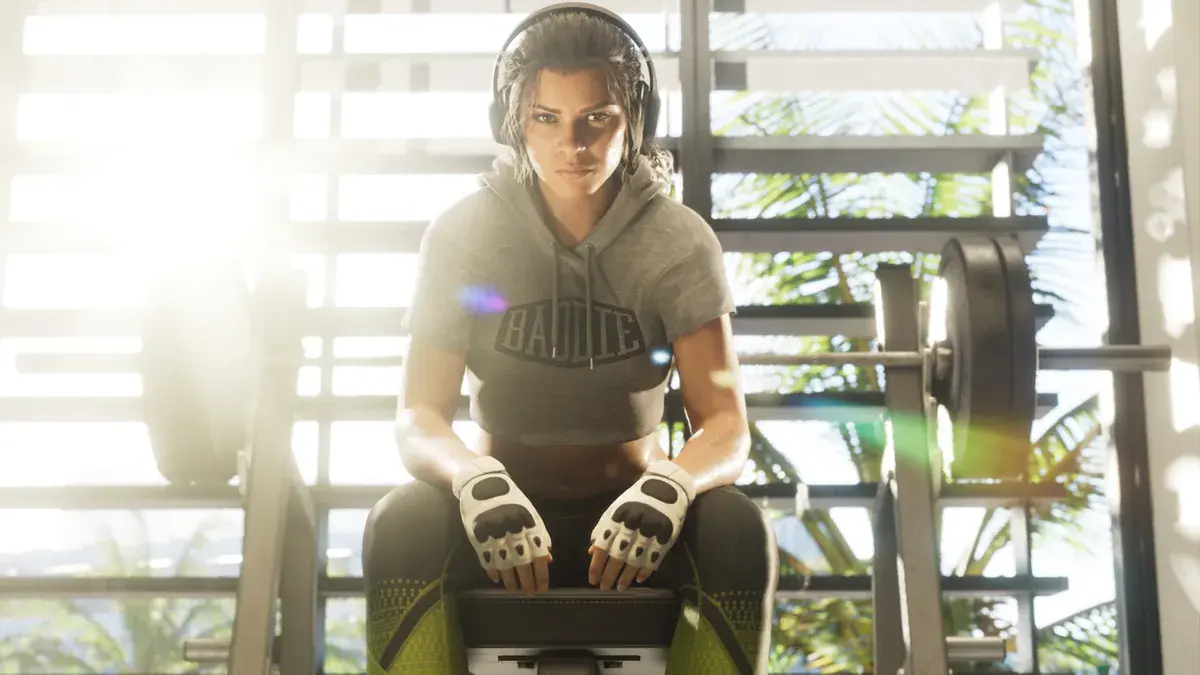 Lucia Caminos assise sur un banc de musculation, casque sur les oreilles, dans une salle de sport ensoleillée de GTA 6