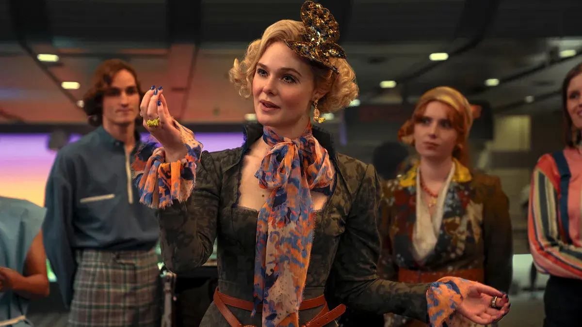 Elle Fanning en jeune Effie Trinket, foulard coloré et broche papillon dans les cheveux, dans Hunger Games : Lever de soleil sur la moisson