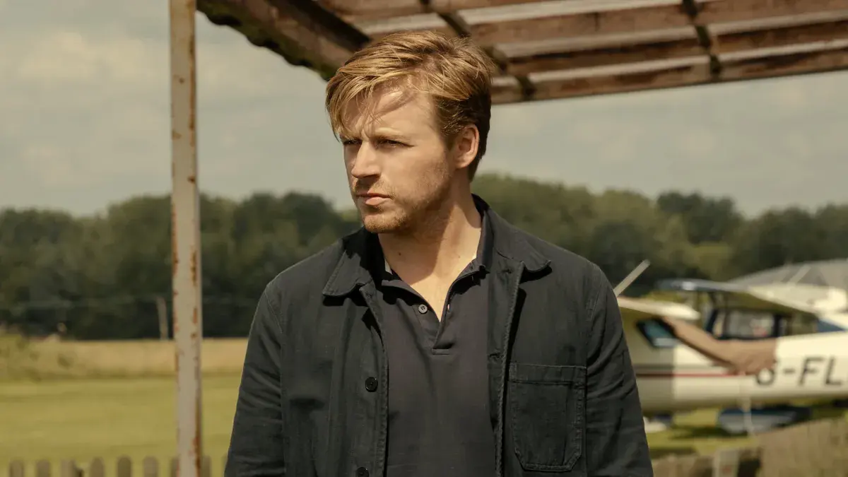 Slow Horses : Jack Lowden en River Cartwright, veste sombre, devant un petit avion de tourisme sur un aérodrome