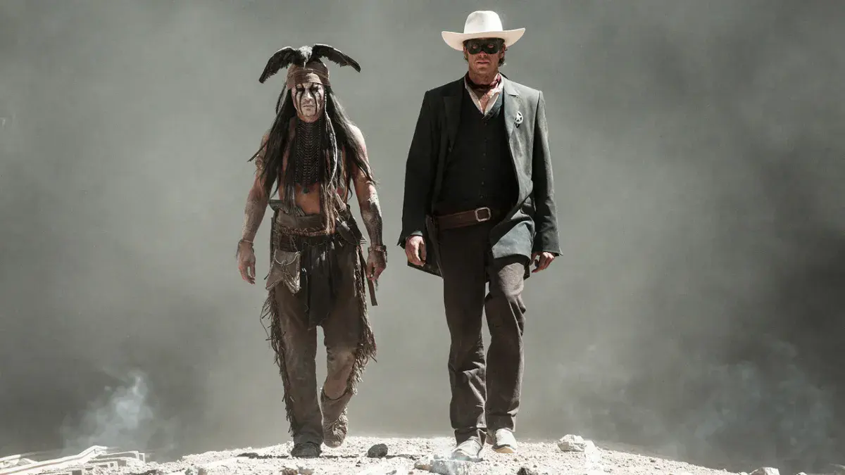 Johnny Depp en Tonto, visage peint et corbeau sur la tête, marche aux côtés d'Armie Hammer masqué et coiffé d'un chapeau blanc dans Lone Ranger