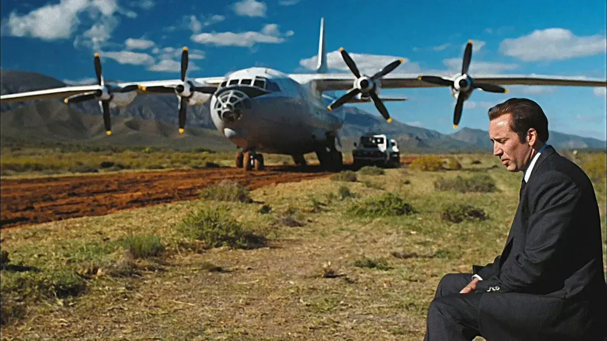 Nicolas Cage en Yuri Orlov, assis près d'un avion cargo Antonov sur une piste de terre dans Lord of War (2005)