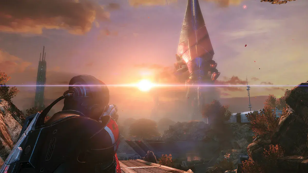 Un soldat en armure, de dos, face à une haute tour qui se découpe dans un coucher de soleil, capture officielle de Mass Effect Édition Légendaire