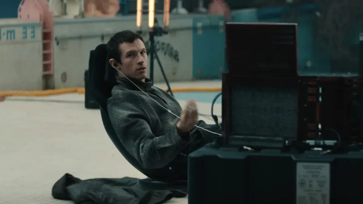 Callum Turner dans le rôle de Case, assis dans un fauteuil de console relié par un câble, dans la bande-annonce de Neuromancien