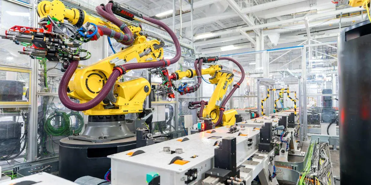 Bras robotisés jaunes et postes d'assemblage de la première ligne de production d'Optimus dans l'usine Tesla de Fremont, en Californie