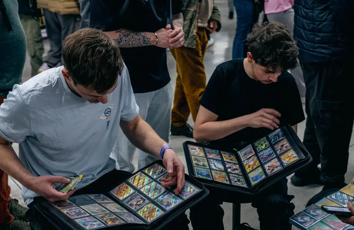 Deux visiteurs feuillettent leurs classeurs de cartes à collectionner Pokémon lors d'une précédente Paris Games Week