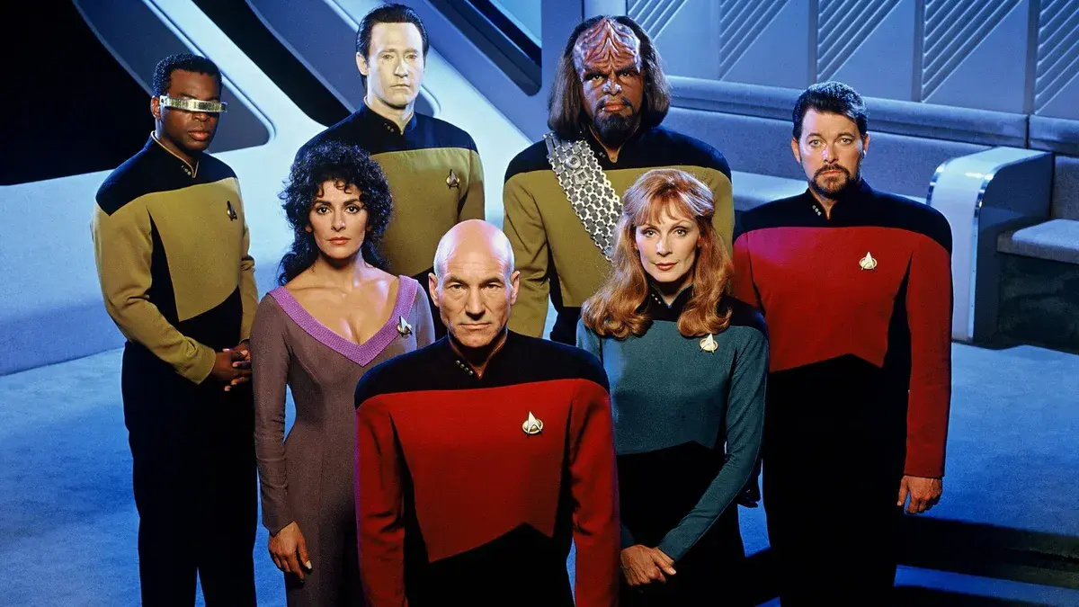 Patrick Stewart en capitaine Jean-Luc Picard, au premier rang de l'équipage de Star Trek: The Next Generation, sur une photo de promotion de la série