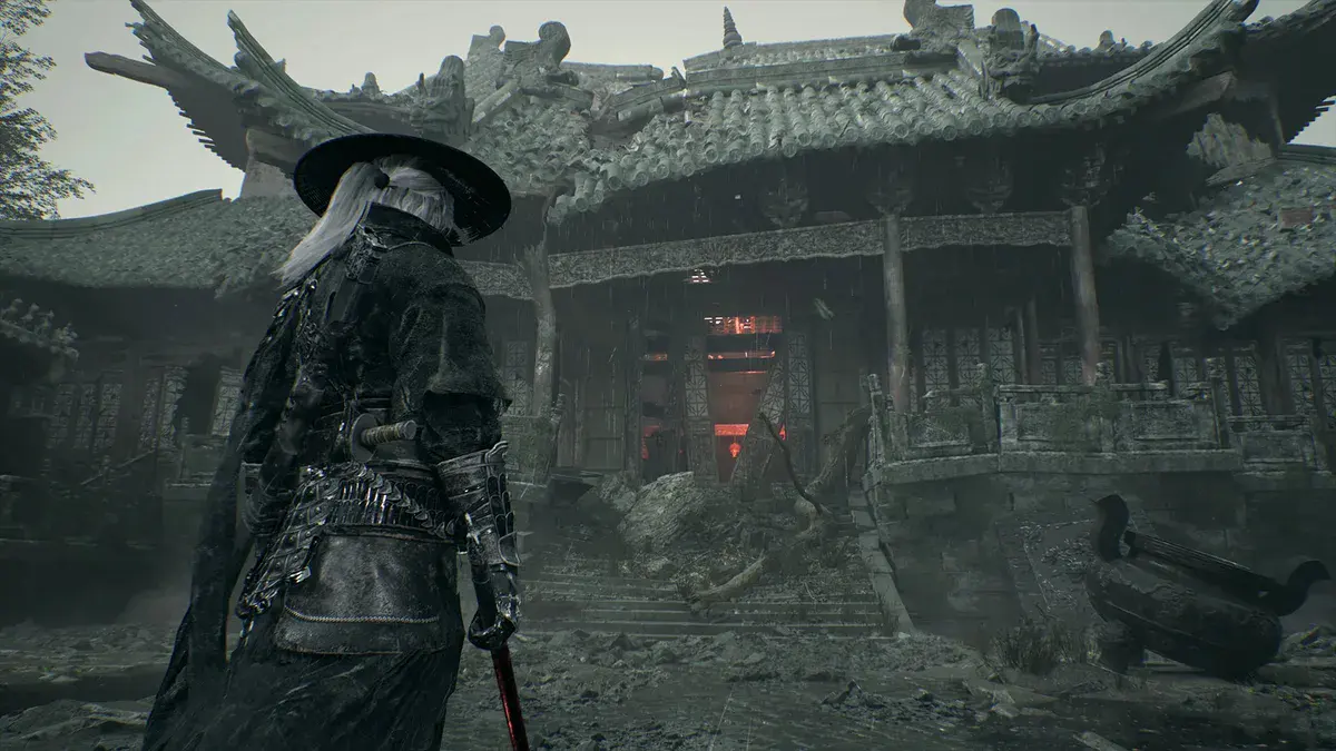 Un épéiste aux longs cheveux blancs, chapeau sur la tête et lame à la main, observe un temple en ruine aux toits de tuiles dans Phantom Blade Zero