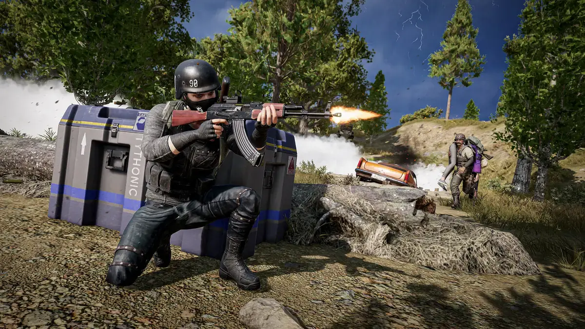 Un joueur casqué tire au fusil d'assaut, accroupi derrière une caisse de largage, dans PUBG: Battlegrounds