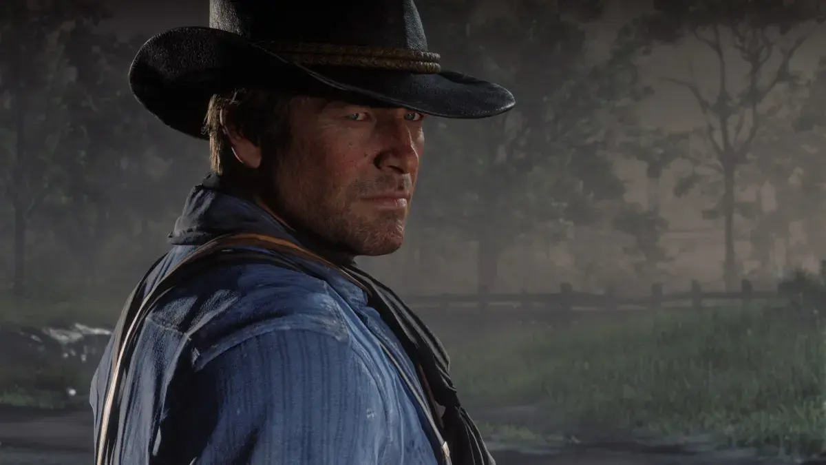 Arthur Morgan, chapeau sur la tête, se retourne en lisière de forêt dans Red Dead Redemption 2