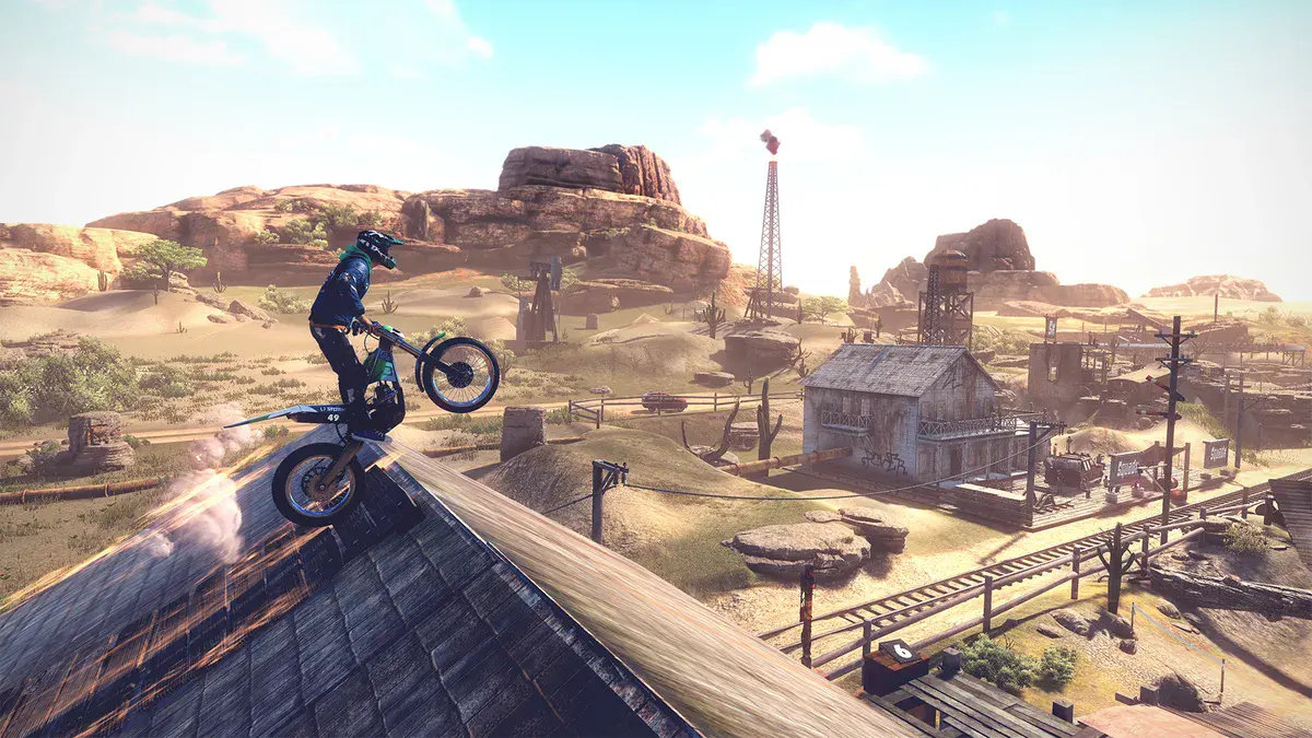 Un pilote de Trials Rising en équilibre sur sa moto au sommet d'un toit, au-dessus d'une ville western en plein désert