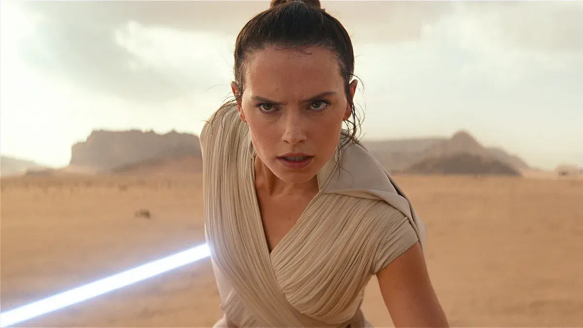 Rey, jouée par Daisy Ridley, sabre laser bleu à la main dans le désert de Pasaana dans Star Wars : L'Ascension de Skywalker