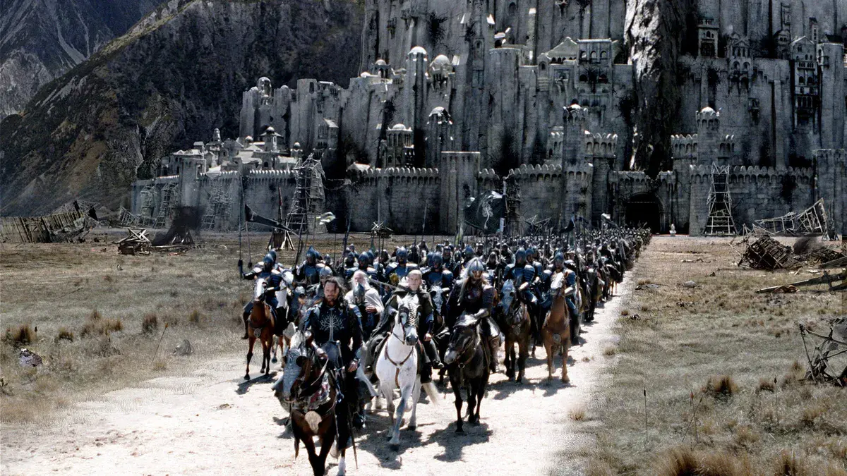 Une armée à cheval avance devant une forteresse de pierre adossée à la montagne, dans Le Seigneur des anneaux : Le Retour du roi