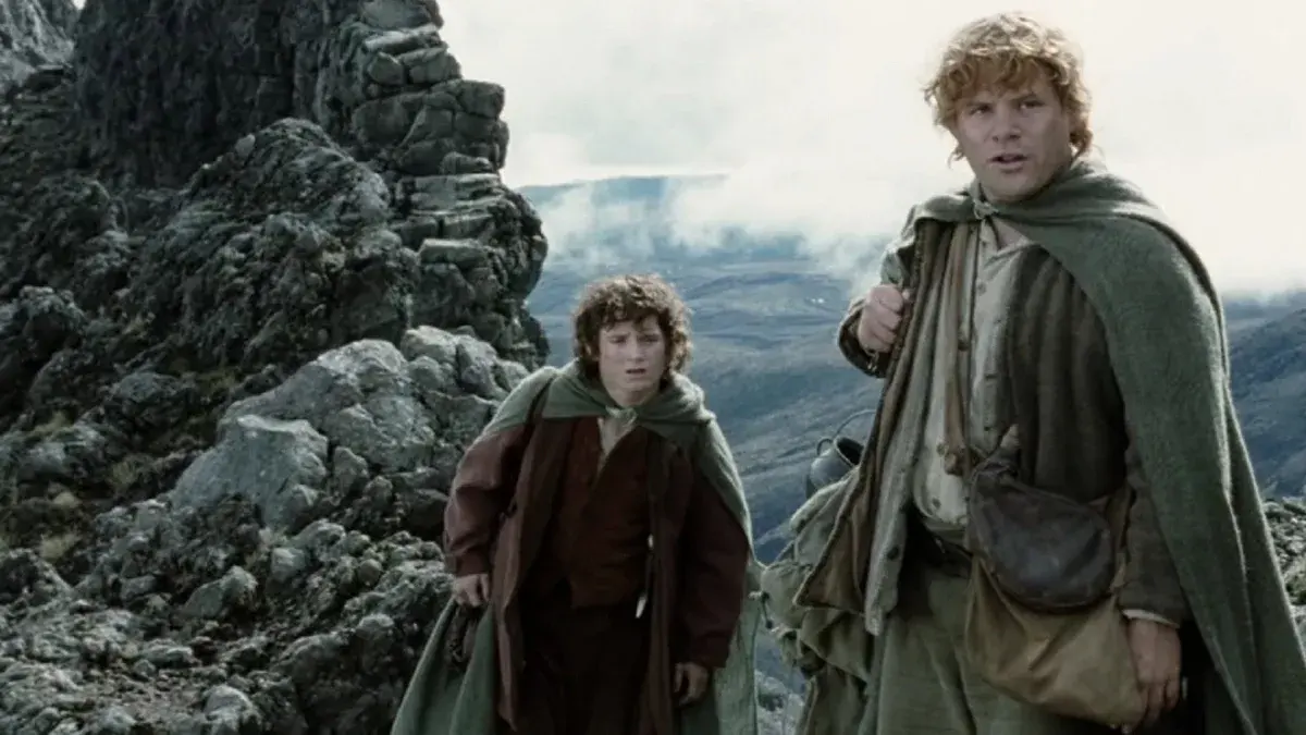 Frodon et Sam, capes vertes sur les épaules, dans un paysage de montagnes et de rochers dans Le Seigneur des anneaux : Les Deux Tours