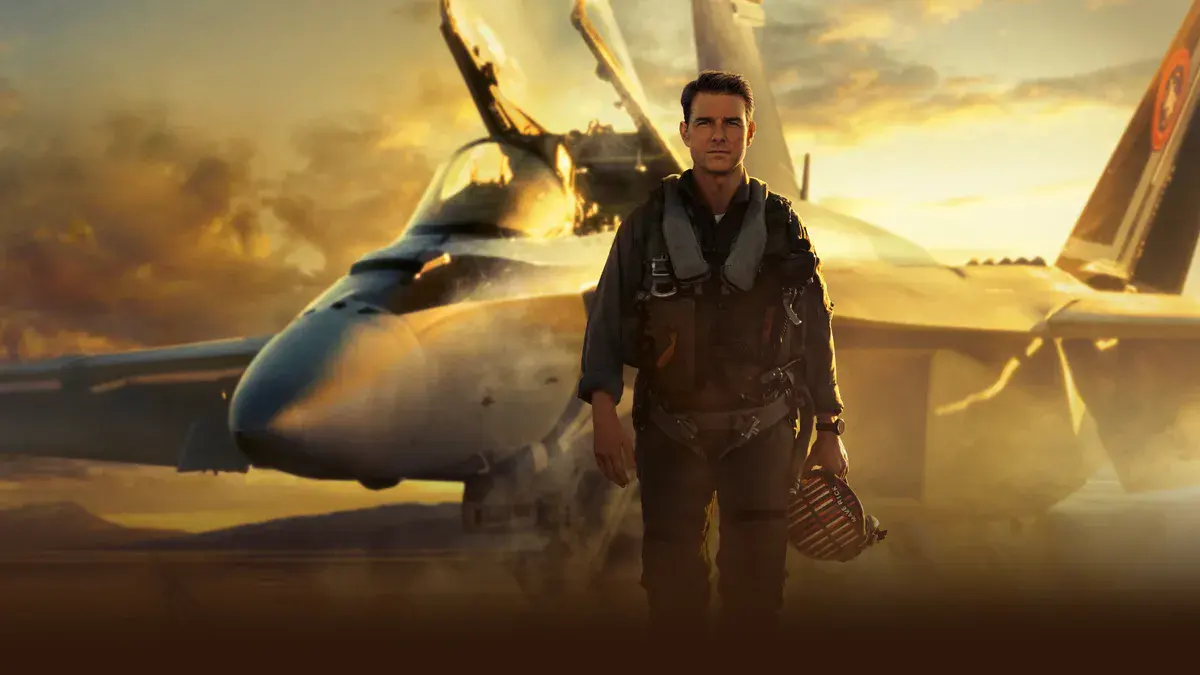 Tom Cruise en pilote de chasse devant un F/A-18 au coucher du soleil dans Top Gun: Maverick, film Paramount