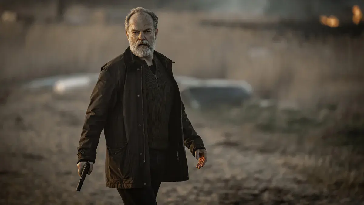 Hugo Weaving en Frank Harkness, barbe blanche et pistolet à la main, avance sur une plage brumeuse dans le final de la saison 6 de Slow Horses