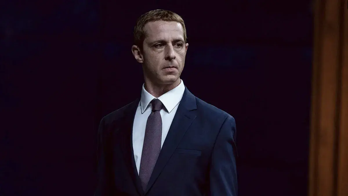 Jeremy Strong, costume bleu marine et cravate, dans le rôle de Mark Zuckerberg dans The Social Reckoning d'Aaron Sorkin