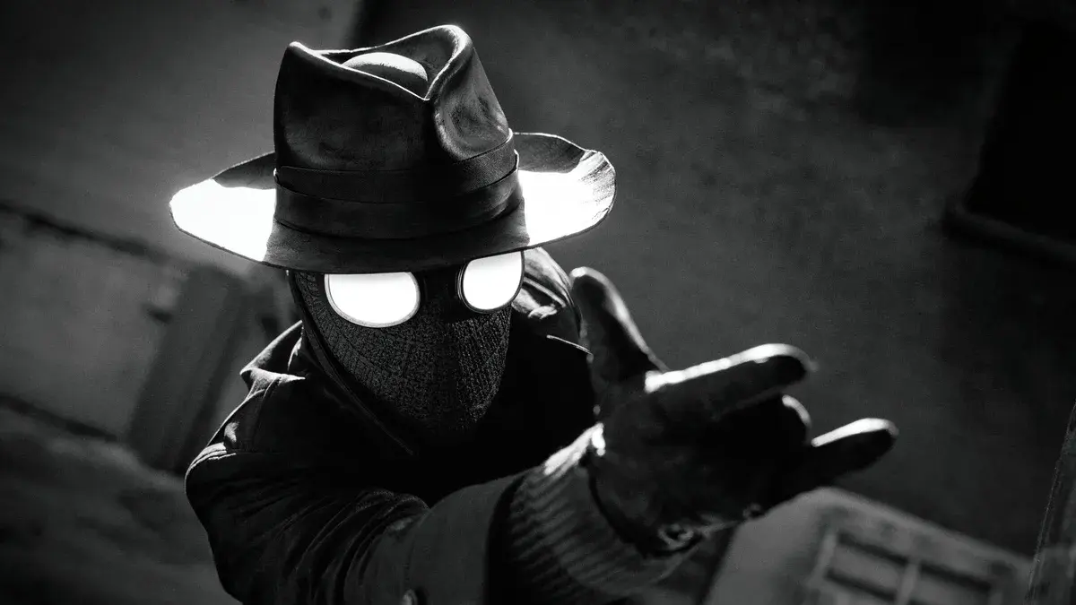 Spider-Noir, chapeau mou et masque aux yeux blancs, tend une main gantée vers l'objectif dans une image en noir et blanc de la série Prime Video