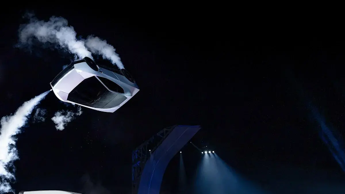 Le nouveau Tesla Roadster blanc retourné en plein saut, traînées d'air comprimé derrière lui, au-dessus d'un camion Tesla Semi lors de sa présentation au Texas