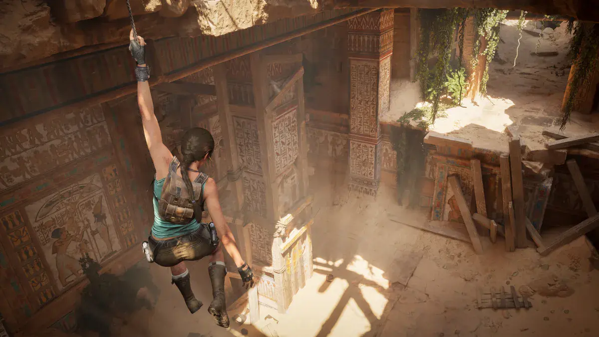 Lara Croft suspendue à son grappin au-dessus d'une salle égyptienne couverte de hiéroglyphes, capture officielle de Tomb Raider : Legacy of Atlantis
