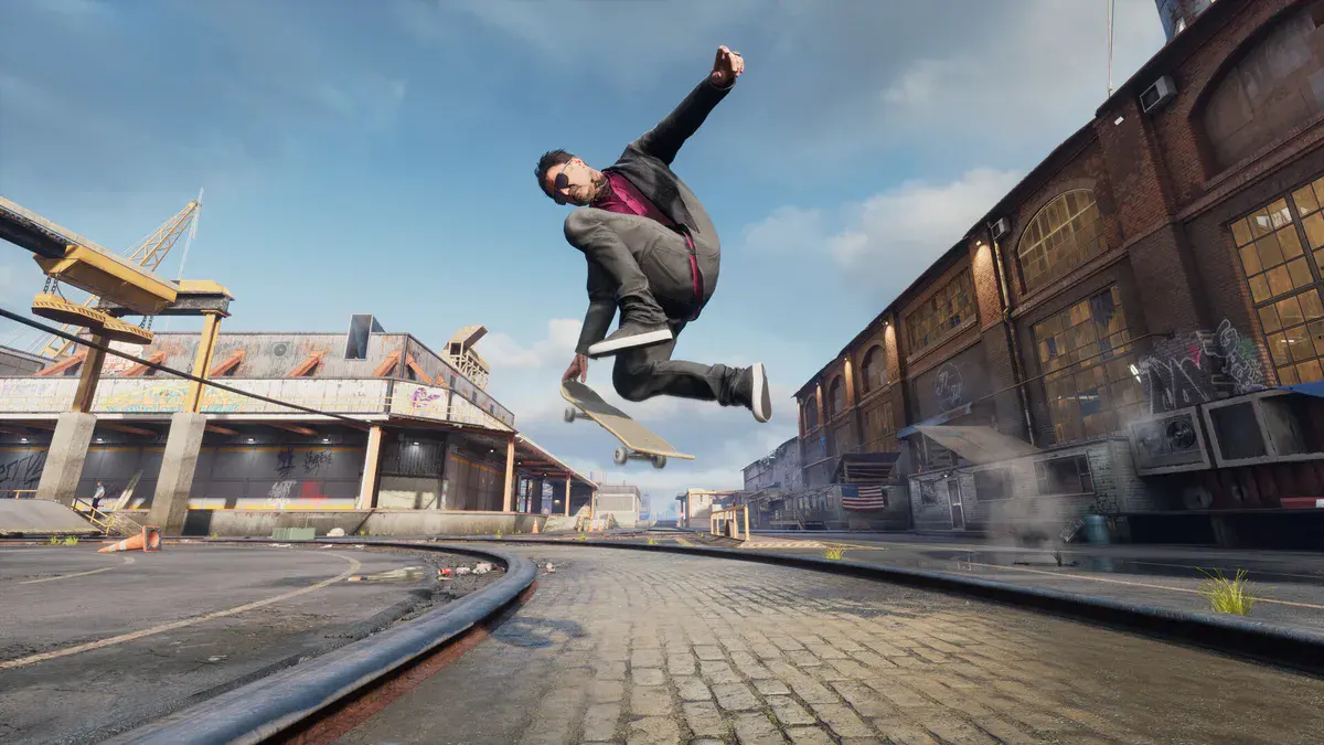 Un skateur en plein saut au-dessus d'une rue pavée bordée d'entrepôts en brique, dans Tony Hawk's Pro Skater 3 + 4