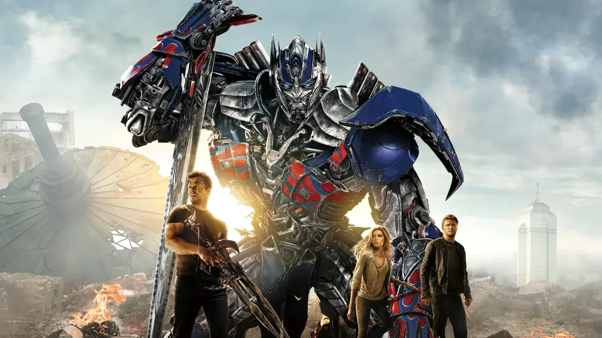 Mark Wahlberg, Nicola Peltz et Jack Reynor devant Optimus Prime dans une ville en ruines, dans Transformers : l'âge de l'extinction de Michael Bay