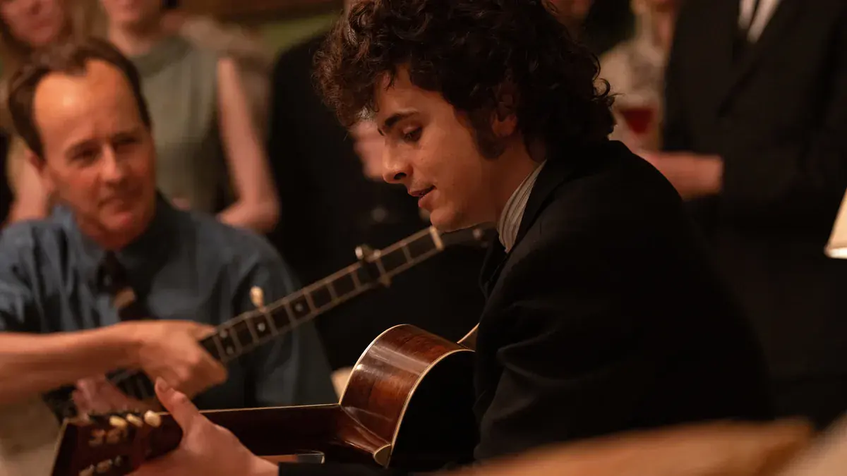Edward Norton en Pete Seeger, banjo à la main, à côté de Timothée Chalamet en Bob Dylan qui joue de la guitare dans Un parfait inconnu