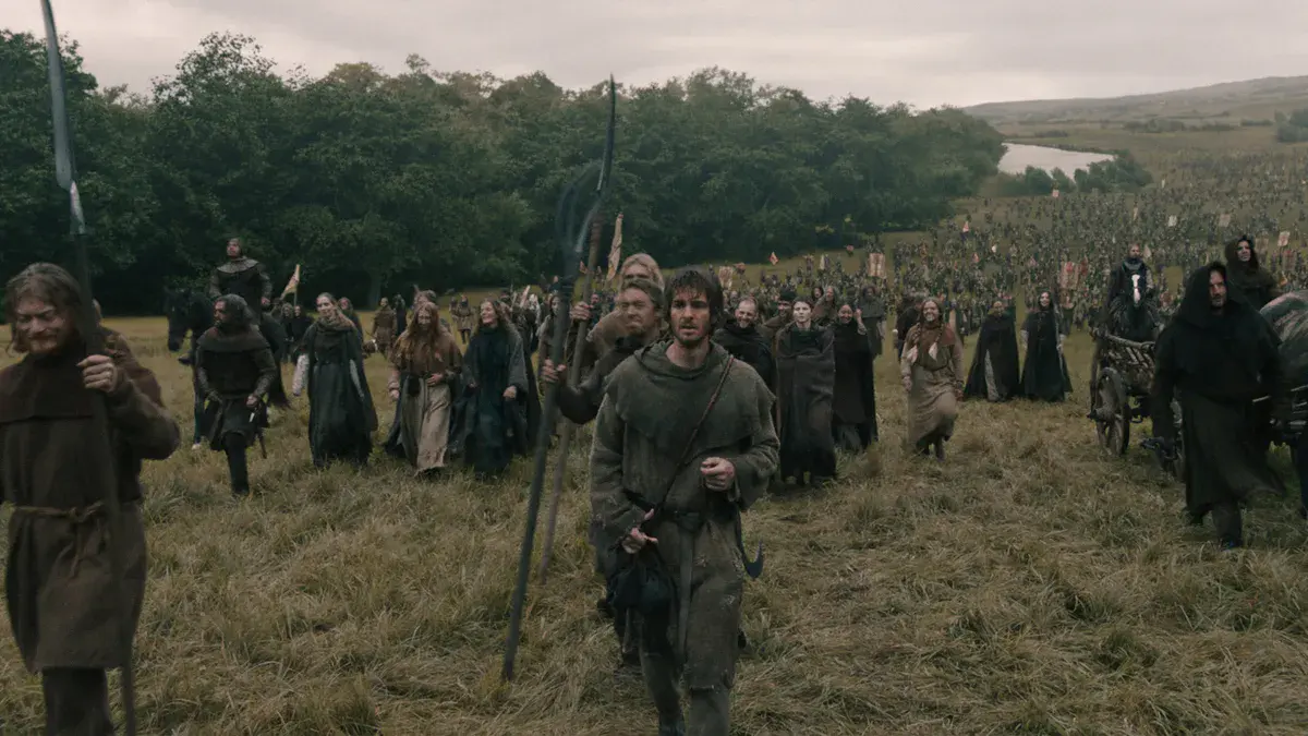 Andrew Garfield, bâton à la main, marche en tête d'une foule de rebelles dans une prairie anglaise dans The Uprising de Paul Greengrass