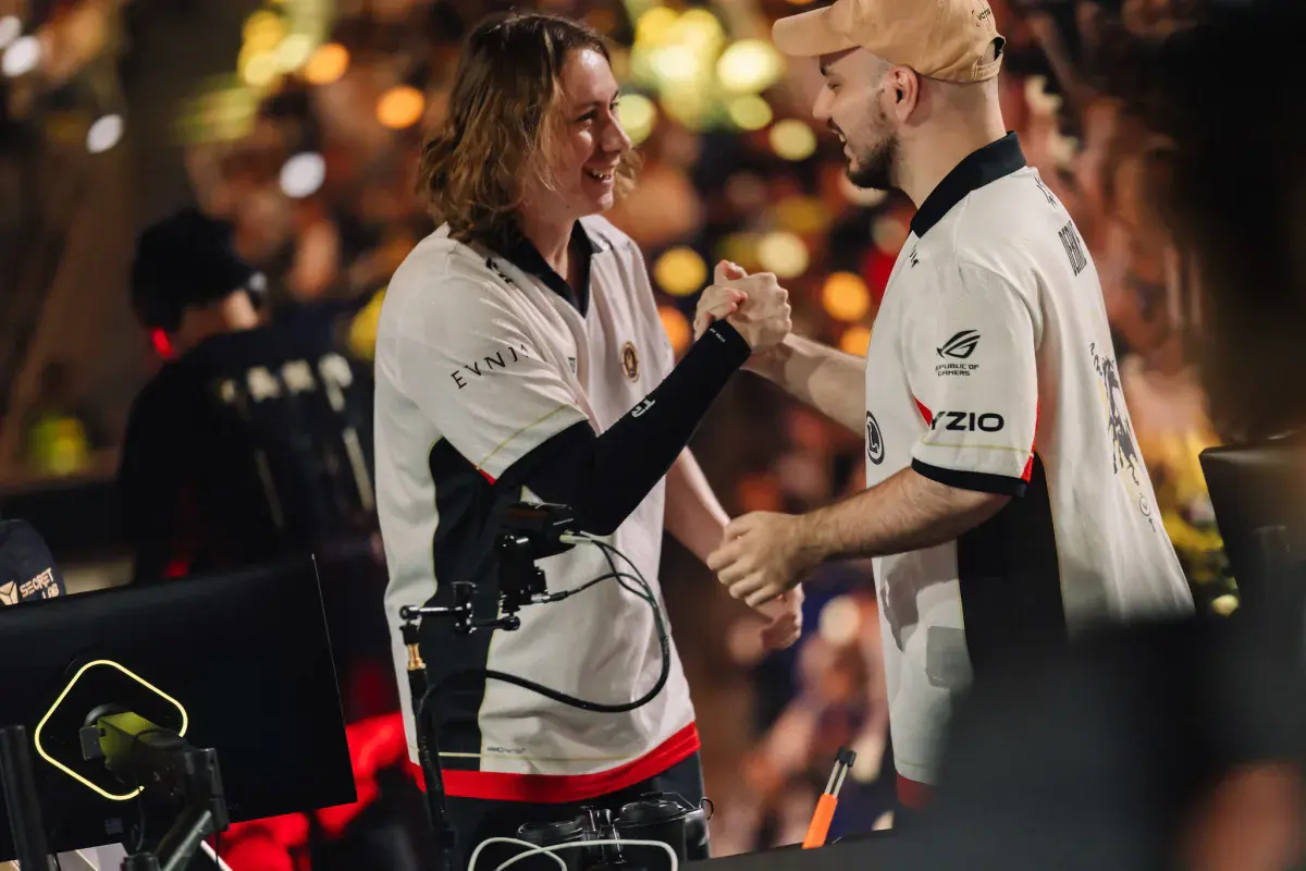 Chronicle et Derke, joueurs de Team Vitality en maillot blanc, se serrent la main en souriant sur la scène de la finale des Valorant Champions 2026 à Shanghai