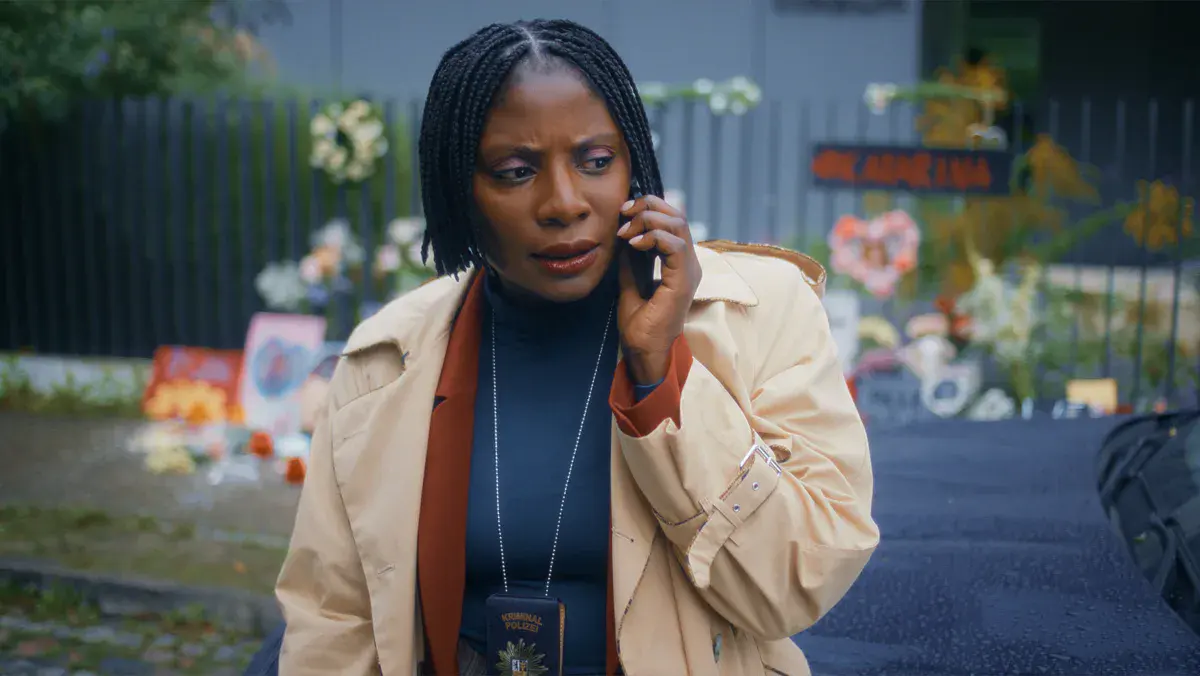 Nikeata Thompson en enquêtrice de la police criminelle, téléphone à l'oreille devant un mémorial fleuri, dans la saison 2 de Where's Wanda? sur Apple TV