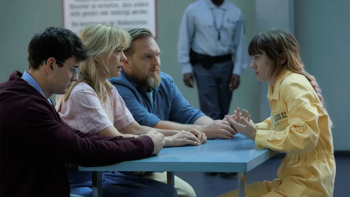 Leo Simon, Heike Makatsch et Axel Stein face à Lea Drinda en combinaison jaune de détenue, au parloir, dans la saison 2 de Where's Wanda? sur Apple TV