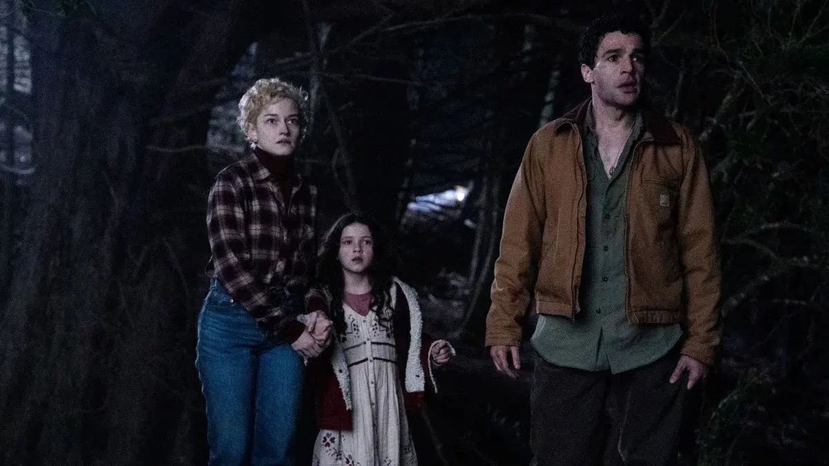 Christopher Abbott, veste de travail marron, scrute la forêt de nuit à côté de Julia Garner et de Matilda Firth dans Wolf Man